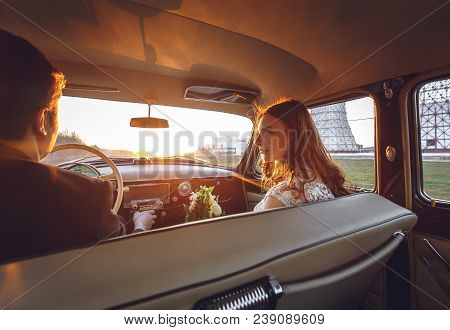 Young Wedding Couple Sitting Smiling Inside Retro Car And Looking At Each Other. Just Married Embrac