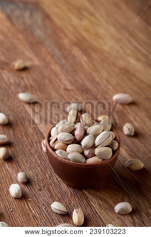Overturned Ceramic Bowl With Pistachios On Wooden Background, Top View, Selective Focus. Some Copy S