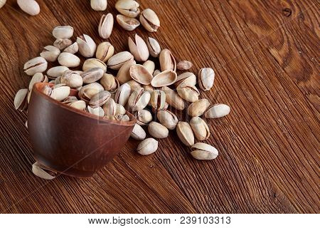Overturned Ceramic Bowl With Pistachios On Wooden Background, Top View, Selective Focus. Some Copy S