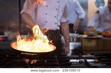 Chef cooking and doing flambe on food in restaurant kitchen