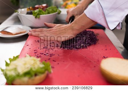 master chef hands cutting salad for a burger in the rastaurant kitchen