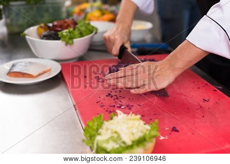 master chef hands cutting salad for a burger in the rastaurant kitchen