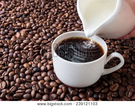 Cup Of Coffee With Milk On Background Of Coffee Beans