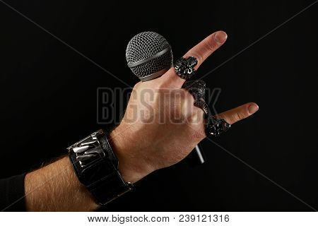Close Up Man Hand With Metal Rings And Bracelet Showing Devil Horns Rock Gesture Sign, Holding Micro