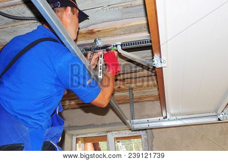 Kyiv, Ukraine - May, 14, 2018: Worker Installing Garage Door Opener System. Garage Door Repair.