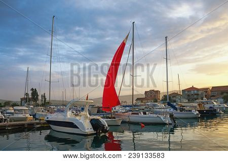 Landscape With Red Sail At Sunset. Fishing Boats In Harbor. Montenegro, Marina Kalimanj In Tivat Cit