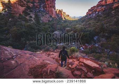 Male Hiker Descending A Steep And Rugged Red Rock Tail From A Scenic Overlook Of Fay Canyon, Coconin