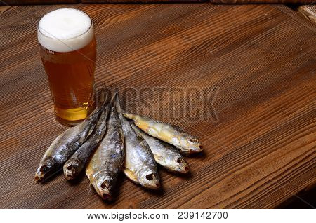 Beer With Dried Fish And Snacks On Wooden Table.