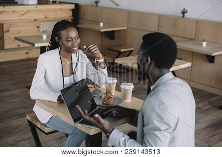 African American Friends Sitting At Table With Laptop In Coffee Shop