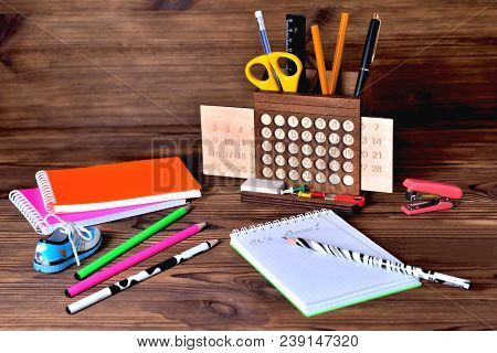 Colorful Notebooks Of Pencils Calendar And A Stapler On A Brown Wooden Background. Inscription In No