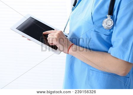 Woman Doctor Using Tablet Computer While Standing Straight In Hospital Office, Closeup. Healthcare, 