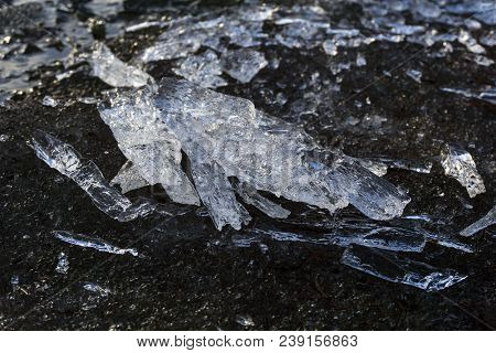 Translucent Melting Ice In Spring On The Sandy Shore Of The Reservoir Closeup