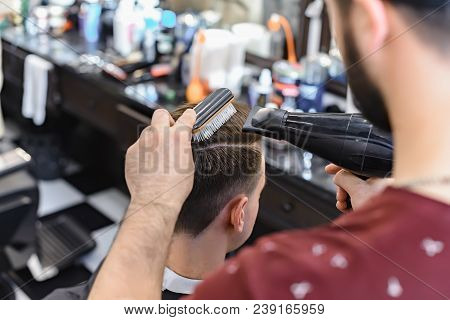 Barber Making Modern Male Hairstyle.barber Makes Hair Styling With A Hair Dryer.