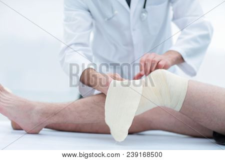 doctor bandaging patient knee