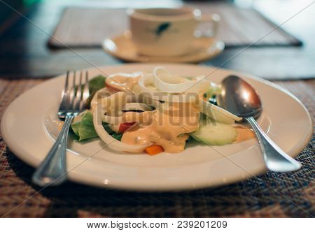 Fresh Caesar Salad On White Plate With Cup Of Coffee Background.