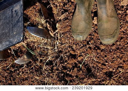 Worker Boots And Motor Cultivator On Soil.