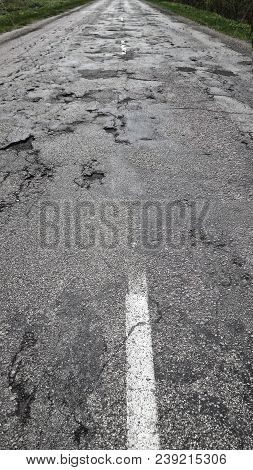 Bad Asphalt Road With White Line. Crack In Grey Asphalt.