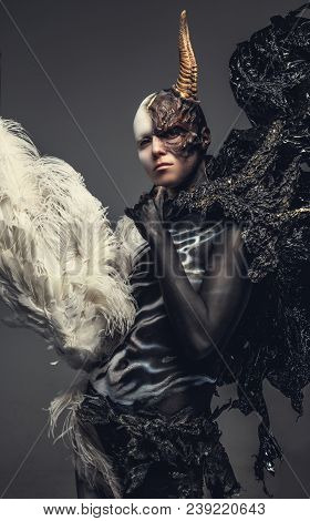 Portrait Of Devil Woman In Black And White Clothes With One Horn On Her Head. Isolated On Grey Backg