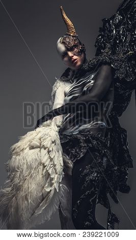 Portrait Of Devil Woman In Black And White Clothes With One Horn On Her Head. Isolated On Grey Backg
