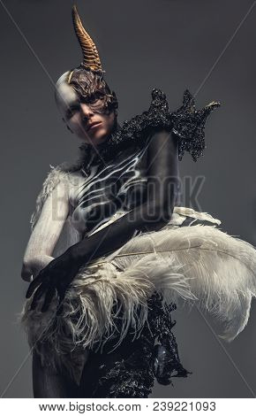Portrait Of Devil Woman In Black And White Clothes With One Horn On Her Head. Isolated On Grey Backg