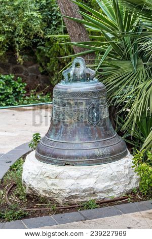 Capernaum, Israel - April 10, 2018: Bell With Patina And Cyrillic Alphabet In Garden In The Greek Or