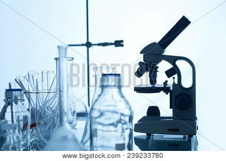 Laboratory Bench With Modern Microscope, Test Tubes, Glass Bottles And Flasks, White Background