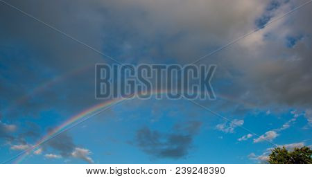 Rainbow At The Background Rain Clouds. Spring Season In The Village. Panorama Sky In The Sunny Day.