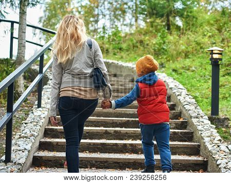 Mom And Son Rising Up The Stairs In The Park Holding Hands.