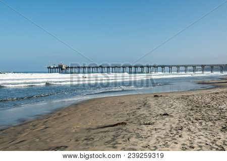La Jolla Shores Beach In San Diego, California, With A Concrete Pier And Surfers In The Background.
