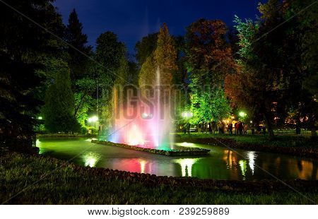 Beutiful Colourful Waterworks During Night In Polanica-zdrój In Poland Reflected In A Small Lake Wit