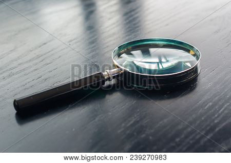 Magnifying Glass On Top Of Black Wooden Table Top