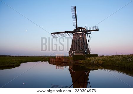 Sunrise With Traditional Dutch Windmills Reflected In The Calm Water Of The Canal.  Landscape With O