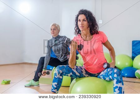 Sporty Slim Women Taking Part In Gym Fitness Class Exercising Sitting On Physioballs Doing Alternate