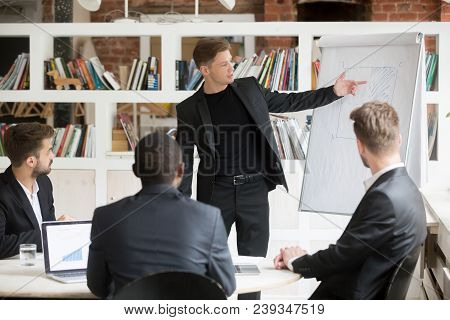 Male Manager Expressing Ideas On Financial Graph Segment Presented On Flipchart To Coworkers On Busi