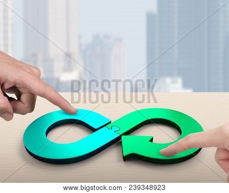 Circular Economy Concept. Two Hands Assembling Arrow Infinity Recycling Symbol Of Jigsaw Puzzle Piec