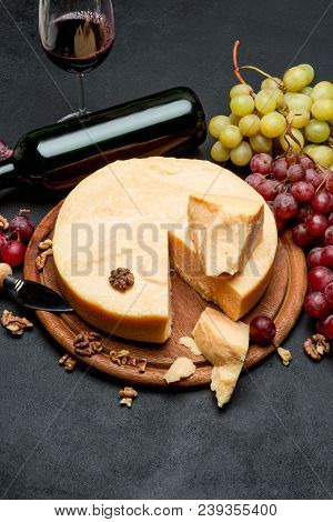 Whole Round Head Parmesan Cheese, Wine And Grapeson Wooden Cutting Board
