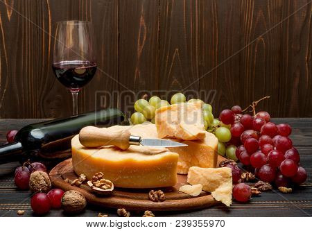 Whole Round Head Parmesan Cheese, Wine And Grapeson Wooden Cutting Board