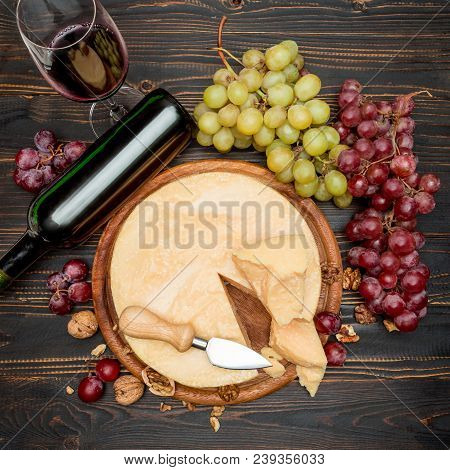 Whole Round Head Parmesan Cheese, Wine And Grapeson Wooden Cutting Board