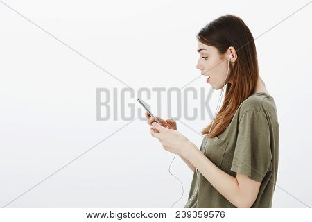 Woman Watching Shocking Video On Smartphone. Attractive Stylish Girlfriend In T-shirt, Holding Smart