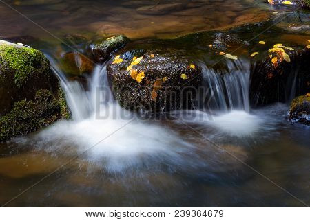 Water Cascade Among The Rocks. Beautiful Nature Background With Yellow Leaves On Wet Stones