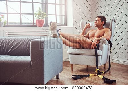 Handsome Shirtless Muscular Man Lying On The Chair, Drink Cup Of Tea, Resting After A Hard Workout A