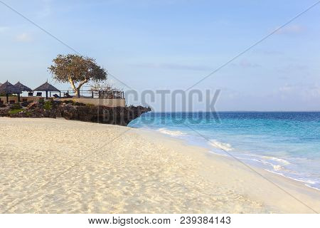 Empty White Sandy Beach On A Tropical Island In Summer With Restaurant Terace Over Turquoise Ocean.