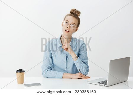 Portrait Of Thougtful Dreamy Woman In Glasses, Gazing Up And Raising Forefinger While Thinking Or Ma