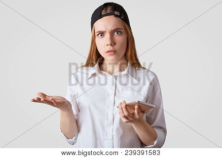 Puzzled Female With Stunned Expresson, Wears Fashionable Cap, Shrugs Shoulders In Bewilderment, Wait