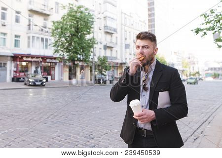 A Businessman Is In A Hurry To Work. Breakfast Is Fast Food On The Road. A Busy Man Is Standing By T