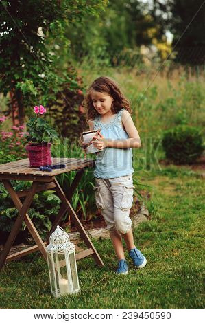 Kid Girl Walking With Candle Holder In Romantic Evening Garden. Decorating Garden Or Backyard In Sum