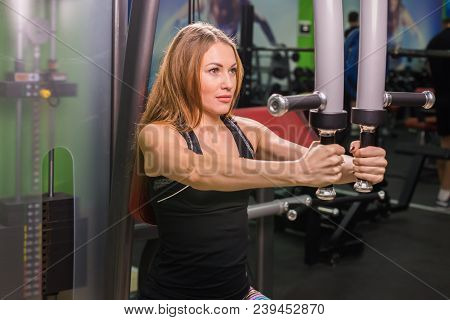 Woman Doing Fitness Training On A Butterfly Machine With Weights In A Gym.