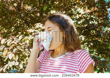 Front View Of A Single Girl Sneezing And Blowing In A Wipe Outdoors With A Green Background