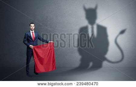 Businessman standing with red cloth in his hand and devil shadow on the background