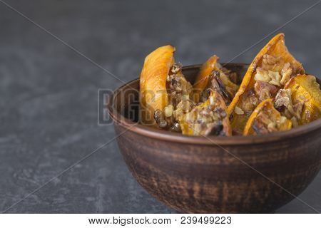 Authentic View Of The Baked Sliced Pumpkin With Honey And Walnuts In A Ceramic Bowl (pial) On A Dark